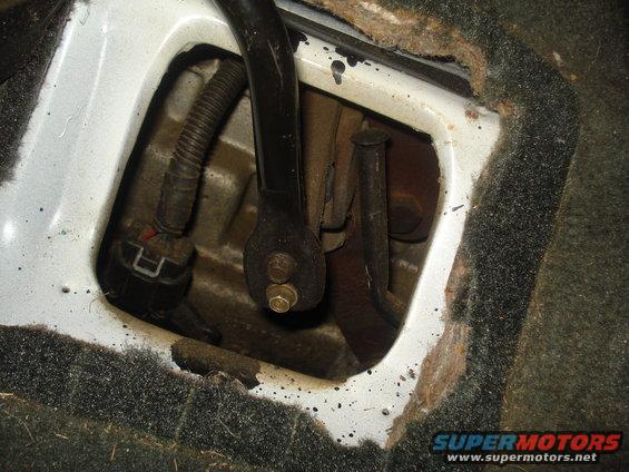 Close-up of vehicle interior floor with exposed mechanical parts and wiring