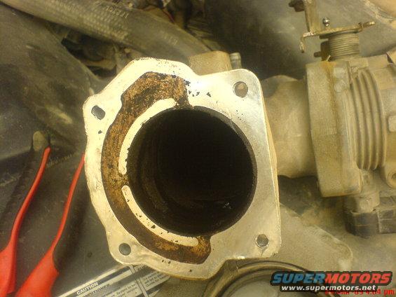 Throttle body with carbon buildup in the EGR channel, next to red tools