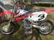 2006 Honda CBR-RR - A red and white dirt bike, possibly a Honda CR, is shown from the side, resting on a stand outdoors.
