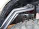 1995 Ford Bronco - This image shows the exhaust headers and part of the suspension system of a vehicle, with a large off-road tire in the foreground.
