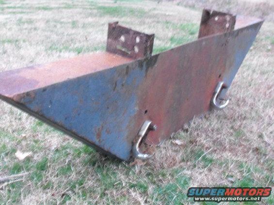 Rusted metal plow attachment with blue paint and metal hooks