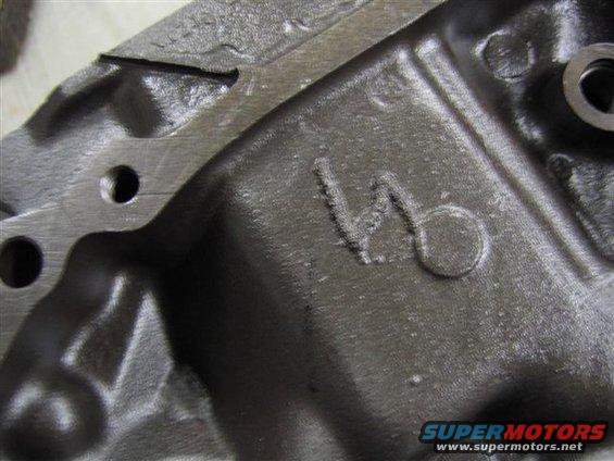 Close-up of a cast metal engine part showing a stamped V6 designation