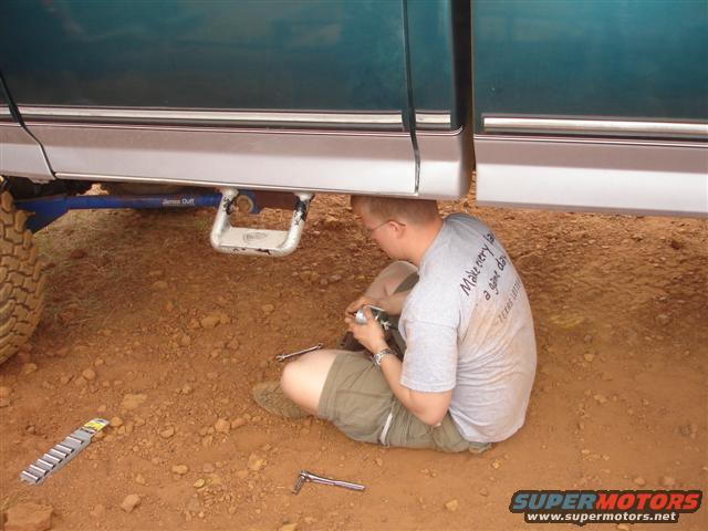 Man working on the undercarriage of a truck, with a step installed on the frame
