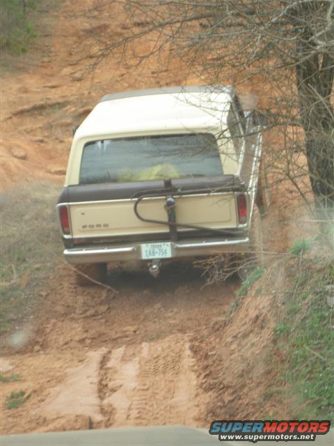 1978 Ford Bronco driving off-road on a dirt path, rear view