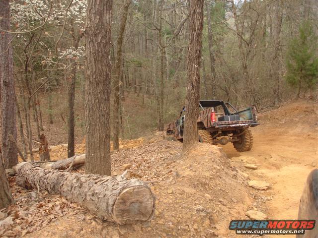 Camouflaged off-road vehicle on dirt trail, rear view