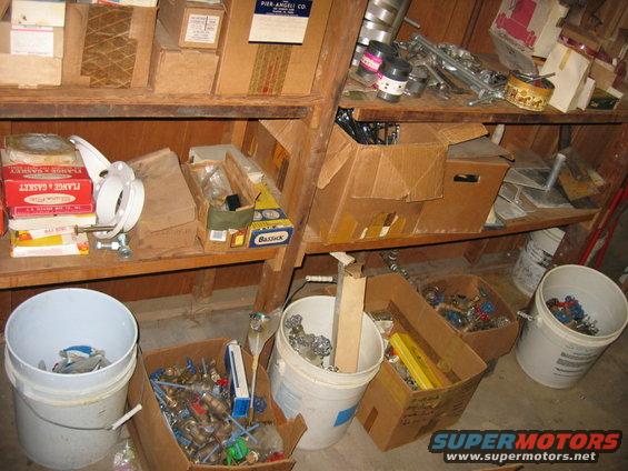 Storage shelves filled with boxes and buckets containing plumbing parts and supplies