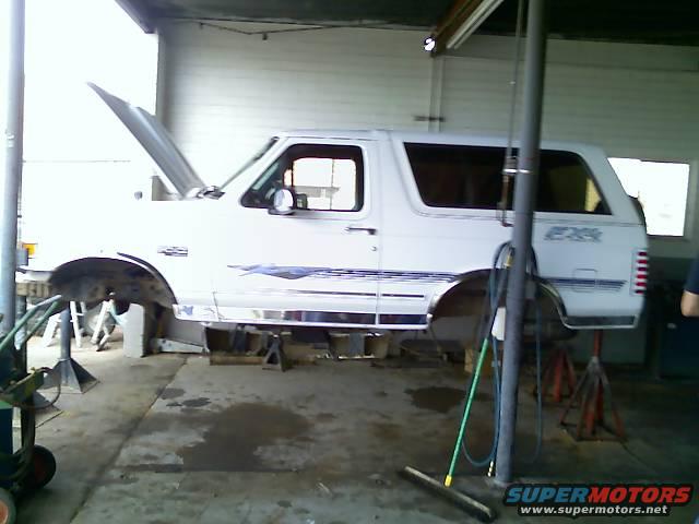 1996 Ford Bronco with hood open, raised on jack stands in a garage