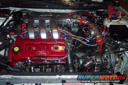 Modified Ford engine bay with red valve cover, turbocharger, and intercooler piping