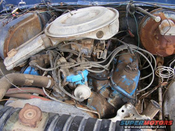 Close-up of a dirty and rusty engine bay with blue painted components.
