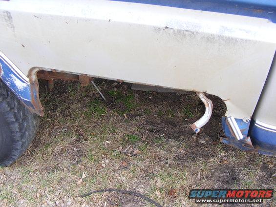 Close-up of rusted lower rear quarter panel and wheel well of a vehicle.