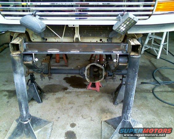 1996 Ford Bronco front axle assembly on jack stands, with custom metal fabrication