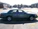 1995 Mercury Grand Marquis - A dark green 1995 Mercury Grand Marquis sedan is seen from the side in a parking lot with apartment buildings in the background.