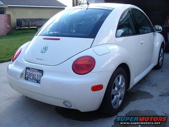 White Volkswagen Beetle parked in a driveway, rear view. License plate reads 5BPV410