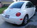 2003 Volkswagen Beetle - The rear of a white Volkswagen Beetle is shown parked in a driveway, with a house and lawn in the background.