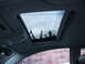 2003 Volkswagen Beetle - Open sunroof shows reflection of trees against a cloudy sky.