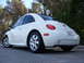 2003 Volkswagen Beetle - Rear view of a white 2003 Volkswagen Beetle, showing its distinctive rounded shape and taillights.
