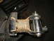 1995 Ford C-350 (Centurion Conversions) - A rusty suspension part is secured in a vise, showing signs of wear and repair.