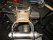 1995 Ford C-350 (Centurion Conversions) - A heavily rusted suspension part, likely from a vehicle, is held in a vise with new hardware attached.