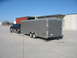 1995 Ford C-350 (Centurion Conversions) - A 1992 Ford pickup truck tows a large silver enclosed trailer on a paved lot under a clear blue sky.