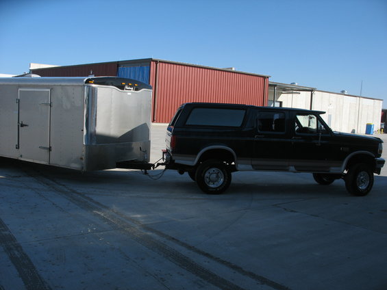 Black 1995 Ford C-350 Centurion Conversions SUV towing a silver trailer