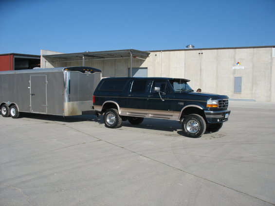 Dark green Ford Bronco towing a silver enclosed trailer