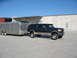 1995 Ford C-350 (Centurion Conversions) - A Ford Bronco SUV tows a silver enclosed trailer in front of a concrete building.