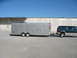 1995 Ford C-350 (Centurion Conversions) - A teal Ford Bronco tows a dual-axle cargo trailer in front of a concrete building.