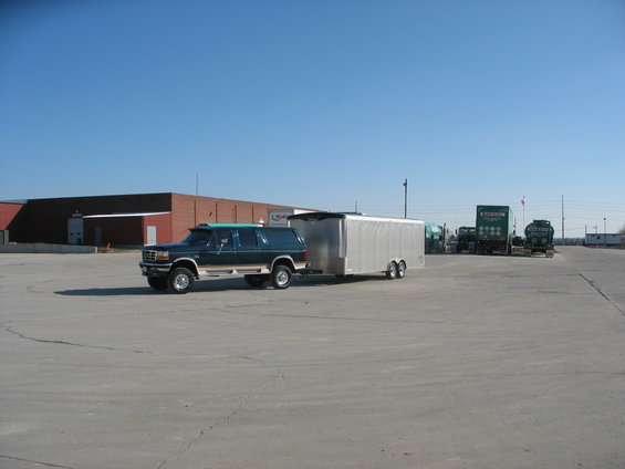 1995 Ford C-350 (Centurion Conversions) towing a silver trailer. Other trucks are parked in the background