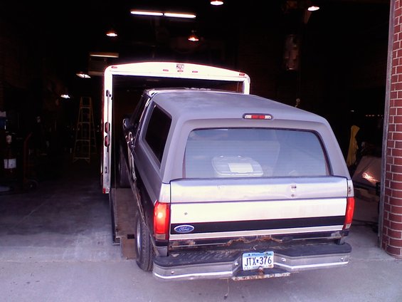 Silver Ford Bronco with a camper shell being loaded into a trailer. License plate JTX-376