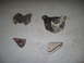 1991 Ford Bronco - Four assorted metal brackets laid out on a concrete surface.