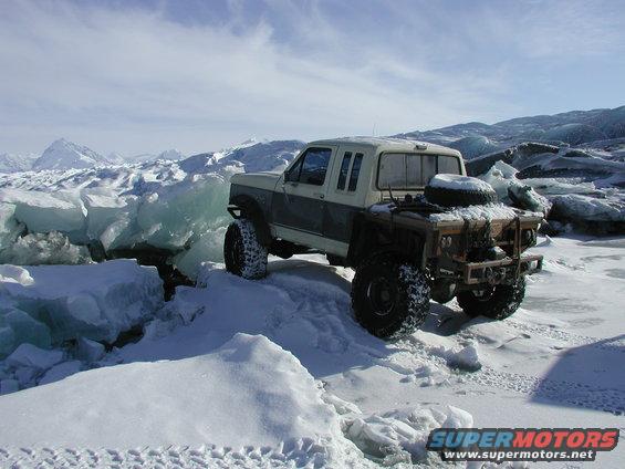 modified 1990 Ford F-250 with large tires on a snowy, icy landscape