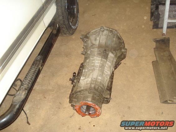 Transmission next to a white vehicle's running board and tire.