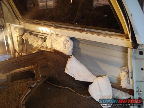 Interior of a vehicle with white packing material stuffed around the dashboard and A-pillar.
