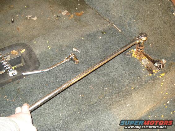 Hand holding metal rod with ratchet and Torx bit on vehicle carpet