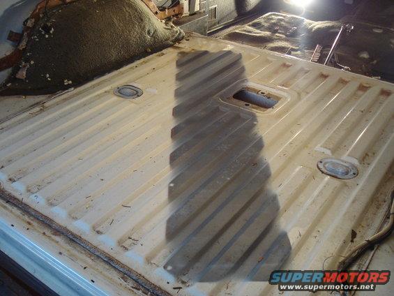 Interior of a vehicle with a ribbed metal floor, showing a shadow cast across it.