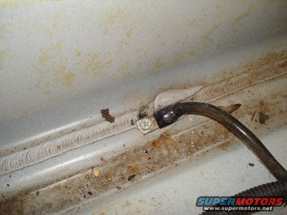 Ground strap bolted to a metal surface with weld seam, and a black wire.