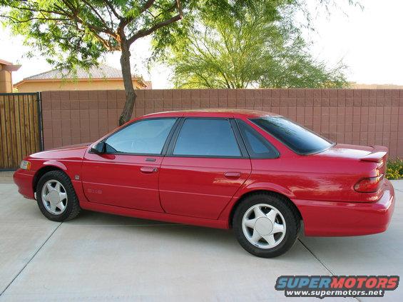 Red 1995 Ford Taurus sedan parked on a concrete driveway