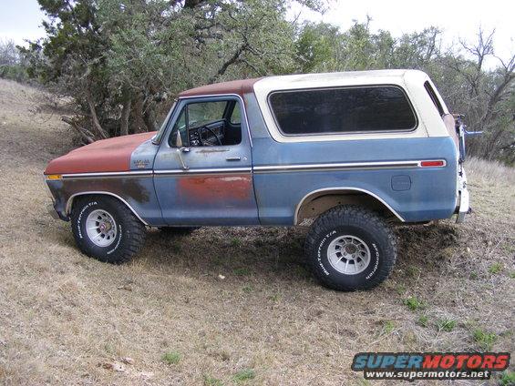 1979 Ford Bronco side view, blue and red paint, white roof, off-road tires.