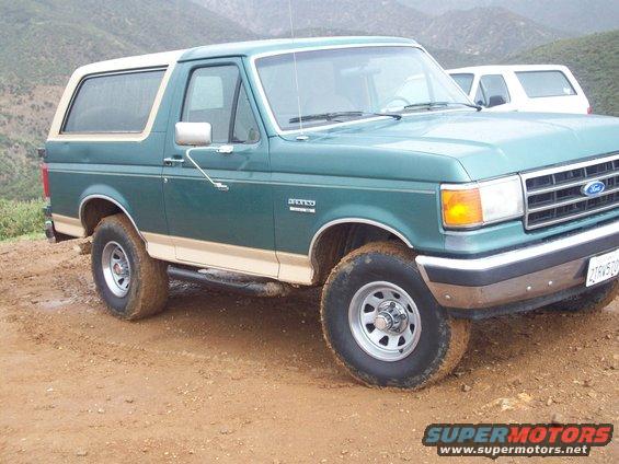 Green 1990 Ford Bronco with tan trim on a dirt road