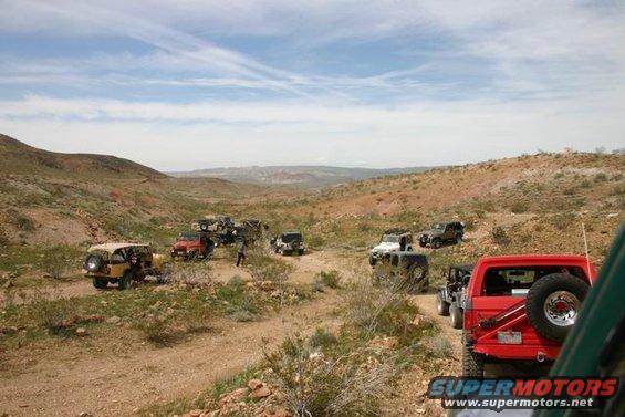 Multiple off-road vehicles on a dirt path in a desert canyon
