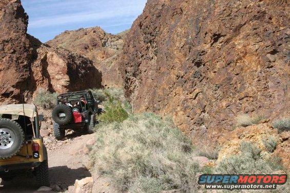 Off-road vehicles in a rocky canyon; Supermotors.net logo