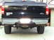 2005 Ford F-250 - Rear view of a black 2005 Ford F-250 pickup truck, showing its chrome bumper, tow hitch, and taillights.