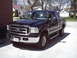 2005 Ford F-250 - This black Ford F-250 Super Duty pickup truck is parked in a driveway on a sunny day.