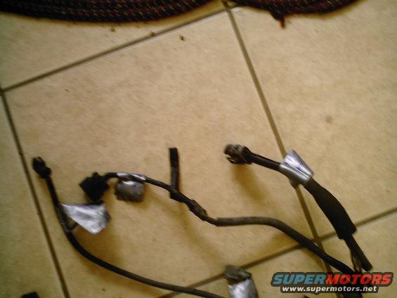 Close-up of a vehicle wiring harness with connectors and tape