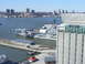 1979 Ford Bronco - An aircraft carrier is docked in a harbor, with buildings and a city skyline visible across the water.