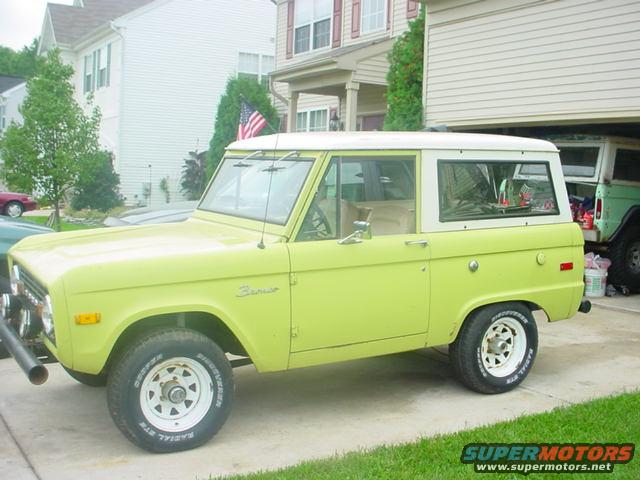 Lime green 1974 Ford Bronco with white top parked outside a house