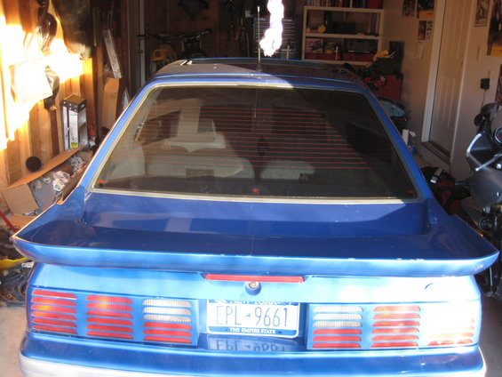 Rear of a blue coupe with a spoiler. Taillights are visible