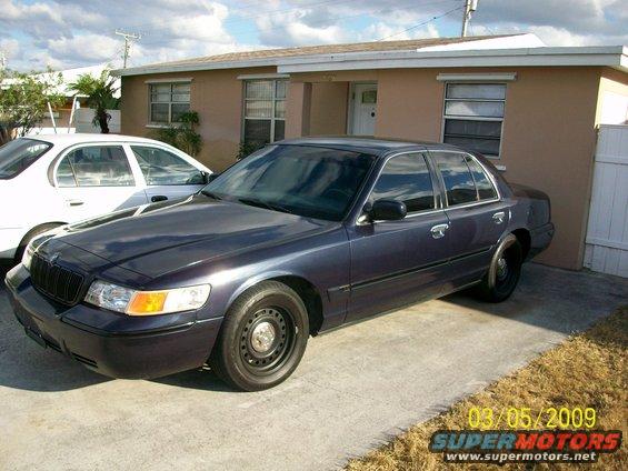 Dark blue sedan parked on concrete, front quarter view. Black steel wheels, chrome trim