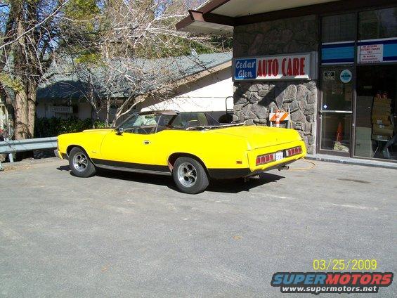 yellow 1973 Mercury Cougar convertible parked outside auto repair shop