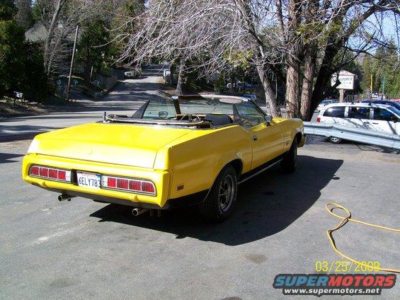 Yellow 1973 Mercury Cougar convertible, rear 3/4 view, parked on asphalt